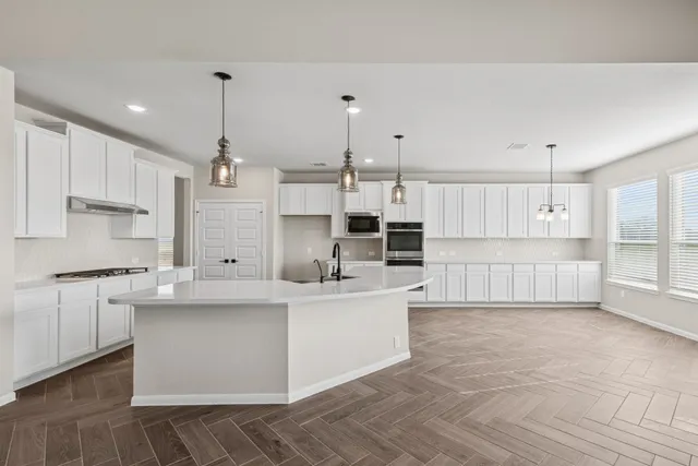 a large white kitchen with kitchen island a sink a stove and a refrigerator