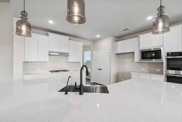 a view of a kitchen with kitchen island stainless steel appliances wooden floor cabinets and a chandelier