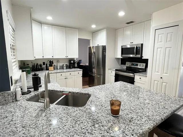 a kitchen with stainless steel appliances kitchen island granite countertop a sink stove and refrigerator