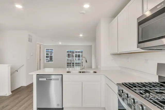 a kitchen with stainless steel appliances a white stove top oven and white cabinets