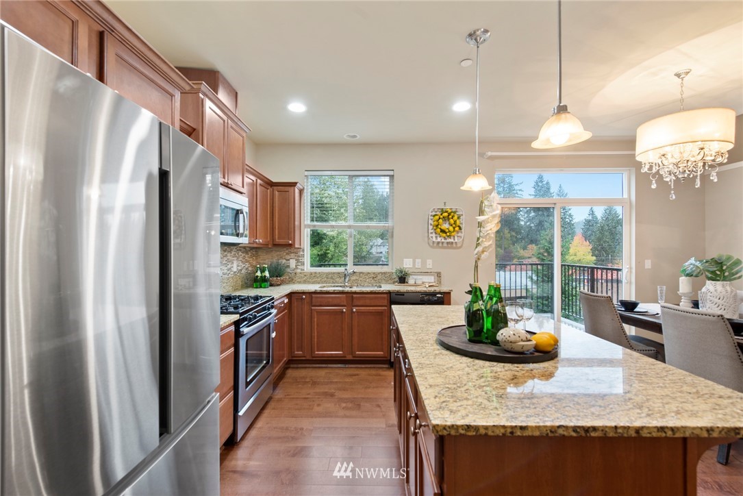 10719 Ross Road, Unit B Bothell, WA 98011 - Photo 6 of 26 a kitchen with stainless steel appliances granite countertop a refrigerator a stove a sink dishwasher a dining table and chairs with wooden floor