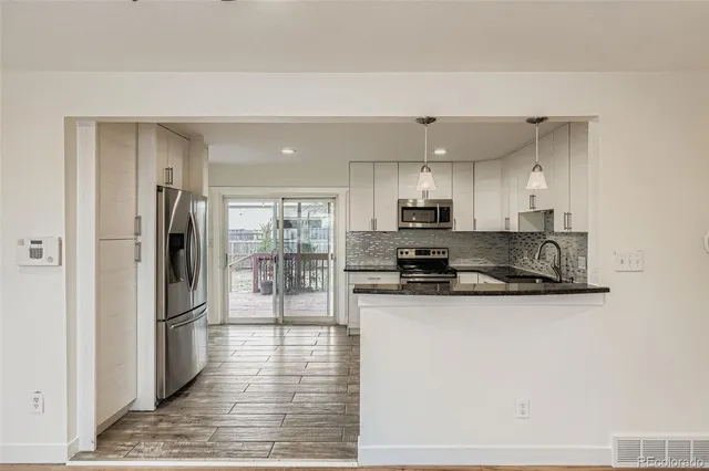 a kitchen with stainless steel appliances granite countertop a refrigerator a stove and a sink with wooden floor