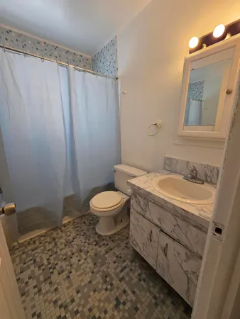 a bathroom with a granite countertop sink toilet and shower