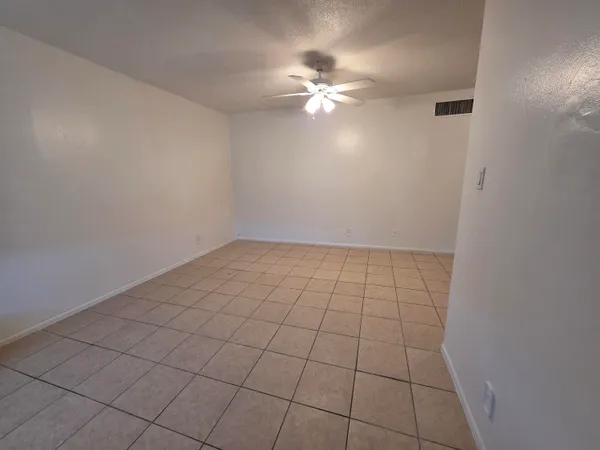 a view of an empty room with chandelier fan