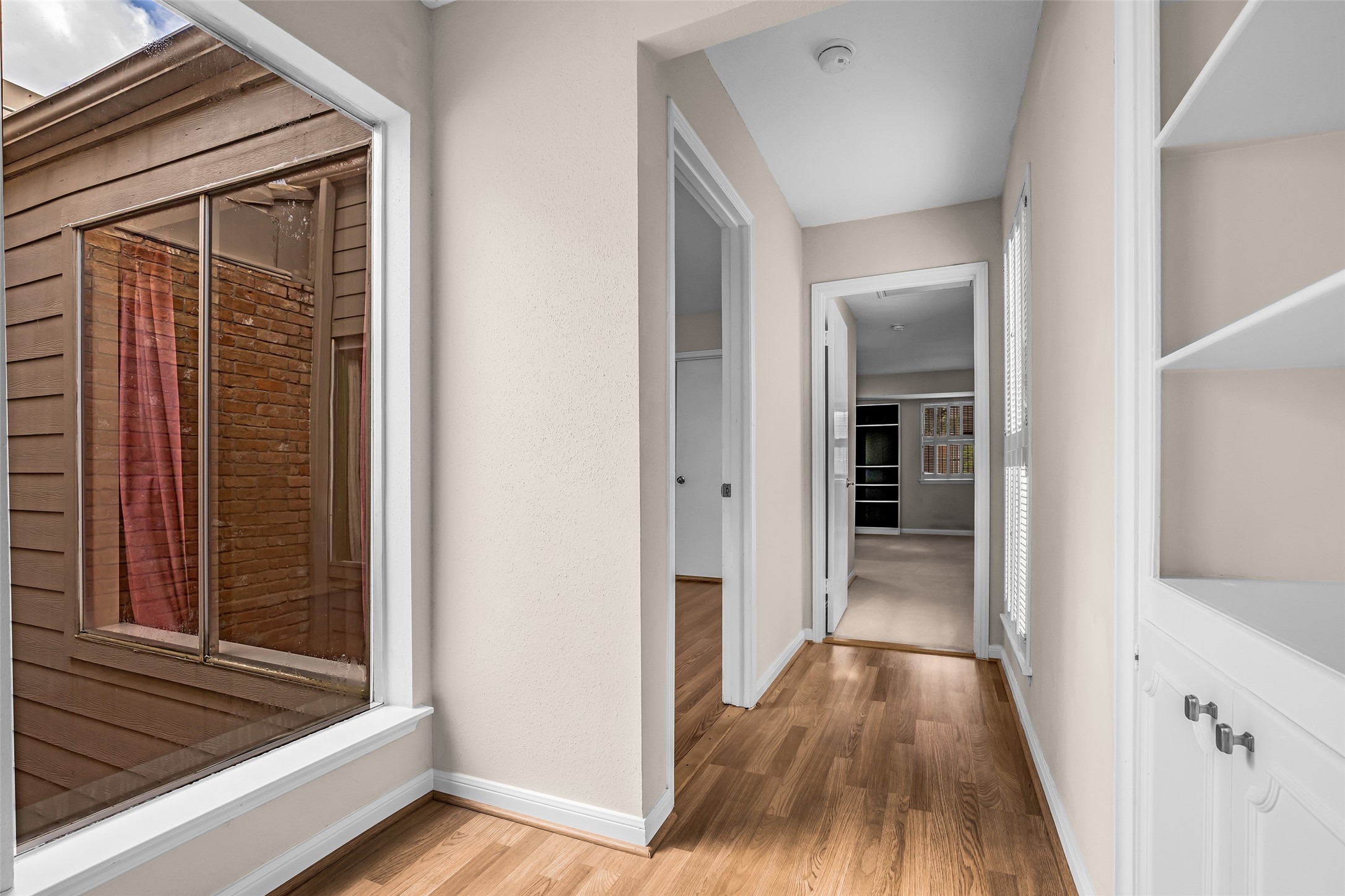 7485 Brompton Street, Unit 7485 Houston, TX 77025 - Photo 30 of 43 A bright, narrow hallway leads to multiple rooms. Large windows on one side offer natural light, while built-in shelving adds storage and functionality.