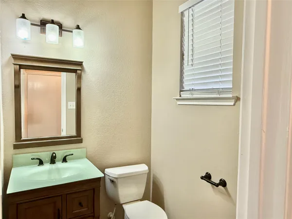 a bathroom with a granite countertop toilet sink and mirror