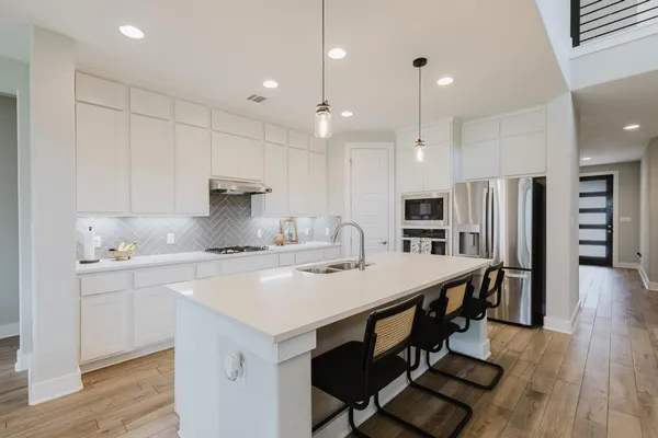 a kitchen with stainless steel appliances a table chairs refrigerator and microwave