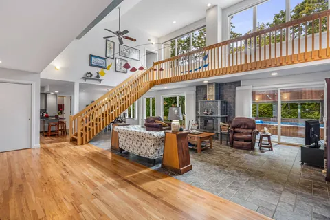 a living room with furniture stairs and a large window