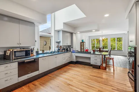 a large white kitchen with stainless steel appliances granite countertop a stove and wooden cabinets