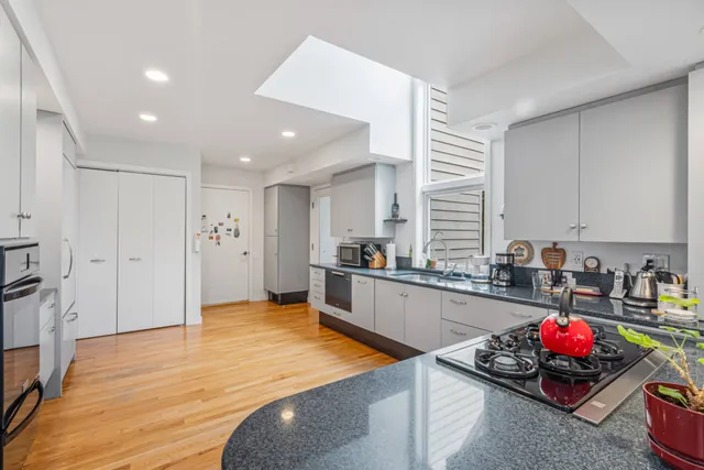 a kitchen with stainless steel appliances kitchen island granite countertop a sink cabinets and wooden floor