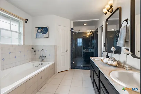 a bathroom with a granite countertop tub a sink a large mirror and a shower