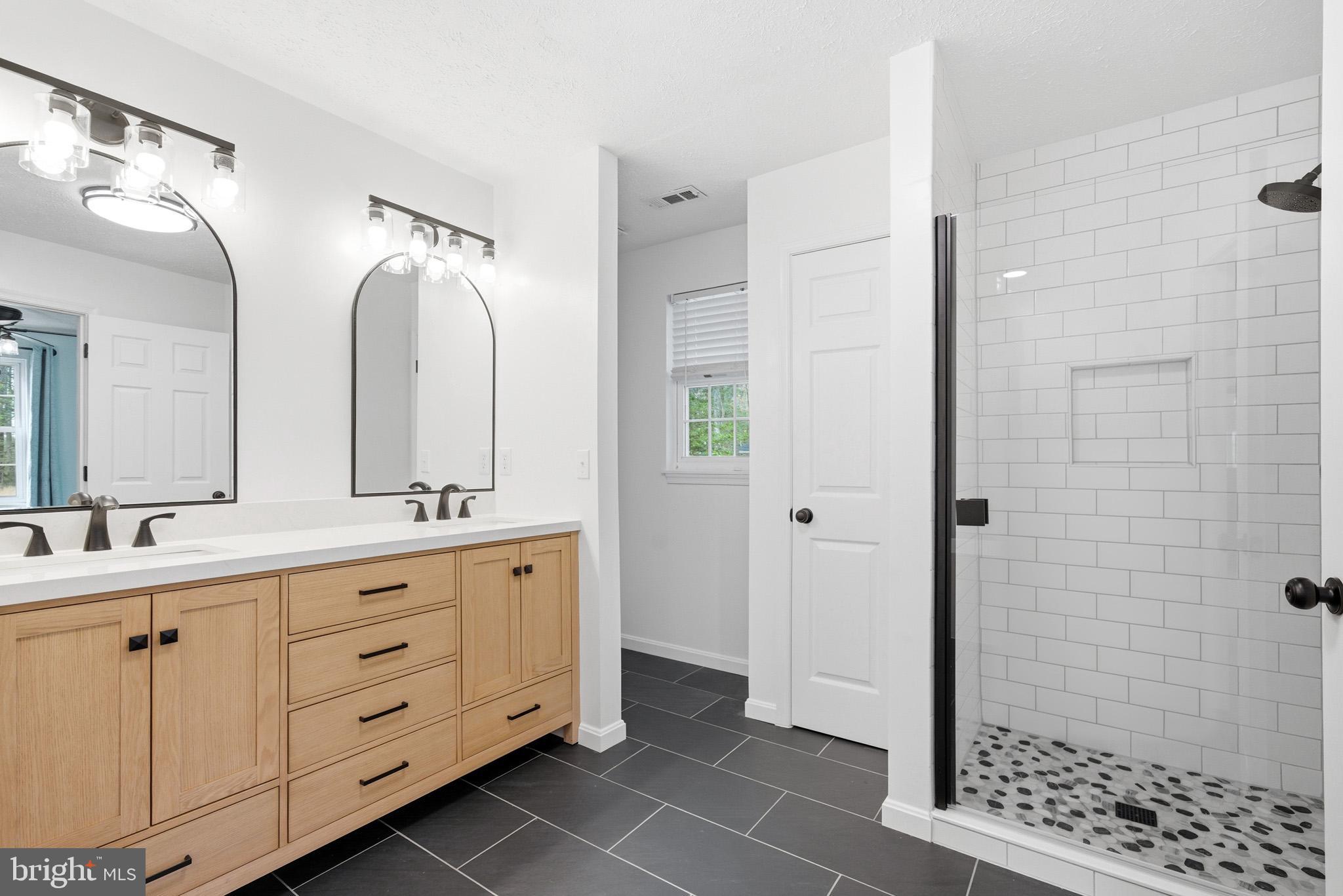 7219 Carrico Mill Road Hughesville, MD 20637 - Photo 20 of 41 a spacious bathroom with a double vanity sink a mirror and a shower