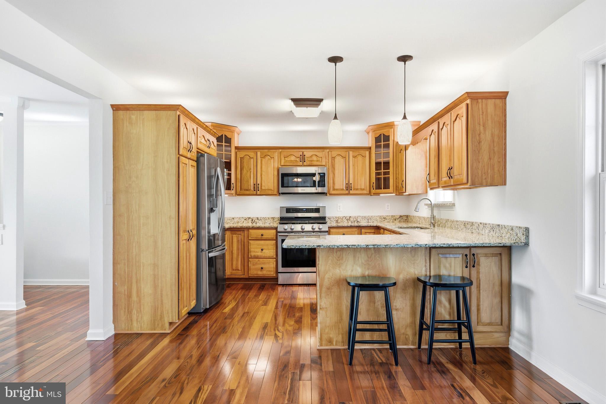 7219 Carrico Mill Road Hughesville, MD 20637 - Photo 10 of 41 a kitchen with stainless steel appliances a stove a sink dishwasher a refrigerator white cabinets with wooden floor