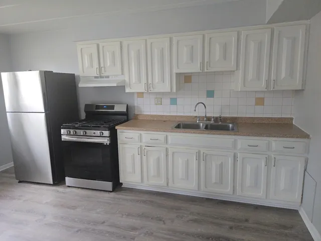 a kitchen with granite countertop white cabinets and stainless steel appliances