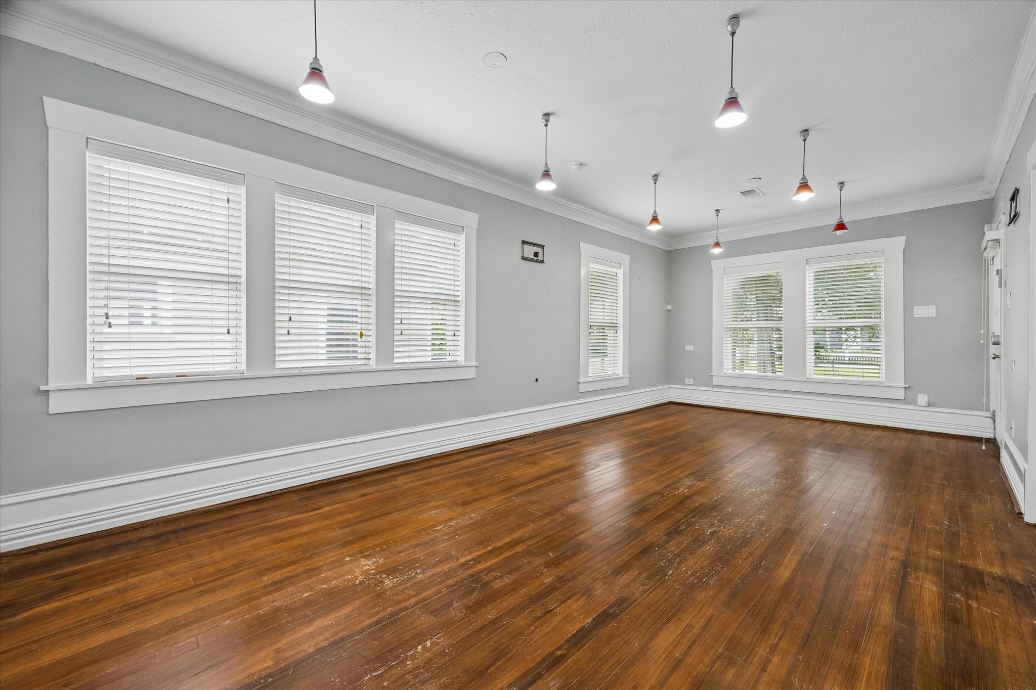 1201 Tulane Street Houston, TX 77008 - Photo 11 of 31 Host friends, stretch out, and enjoy a home that feels open without losing its historic soul. The oversized windows fill the space with natural light, while warm hardwood floors, crown molding, and updated pendant lighting keep the room feeling stylish and full of Heights character.