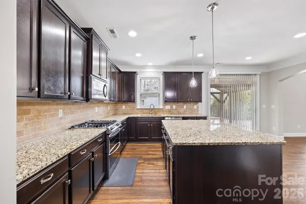 a large kitchen with a large counter top space a sink stainless steel appliances and cabinets