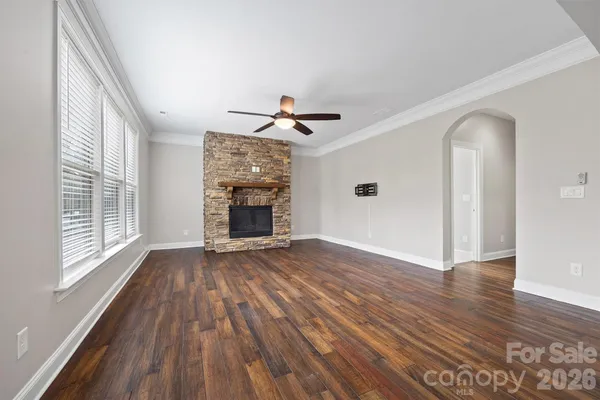 an empty room with wooden floor a ceiling fan and windows