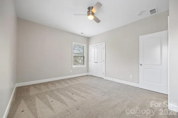 a view of an empty room and chandelier fan