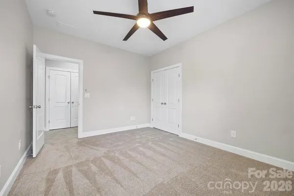 a view of an empty room with chandelier fan and wooden floor