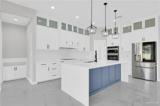 a kitchen with stainless steel appliances kitchen island granite countertop a refrigerator a oven and white cabinets with wooden floor