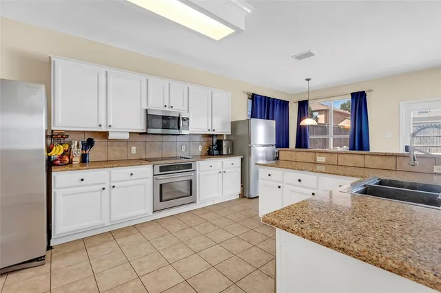 a kitchen with granite countertop white cabinets sink and stainless steel appliances