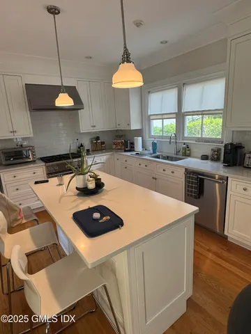 a kitchen with stainless steel appliances granite countertop a sink a stove a dining table and chairs