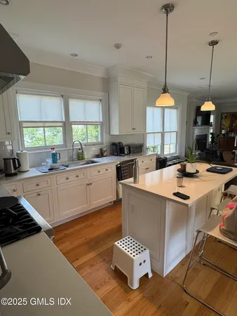 a kitchen with stainless steel appliances granite countertop a sink a stove and a wooden floors