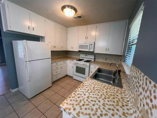 a kitchen with a refrigerator sink and cabinets