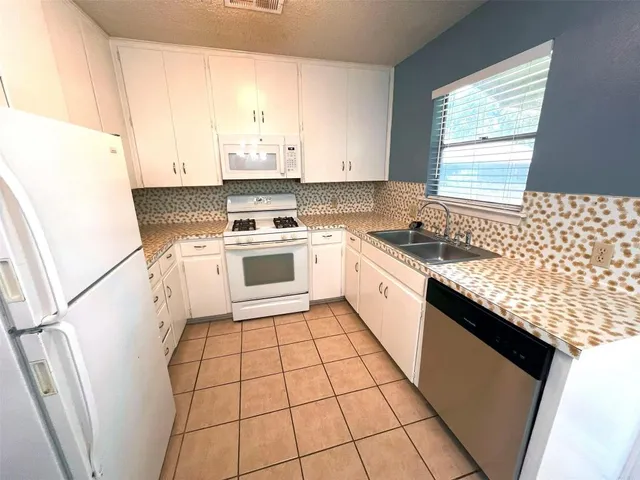 a kitchen with a sink a stove top oven and cabinetry