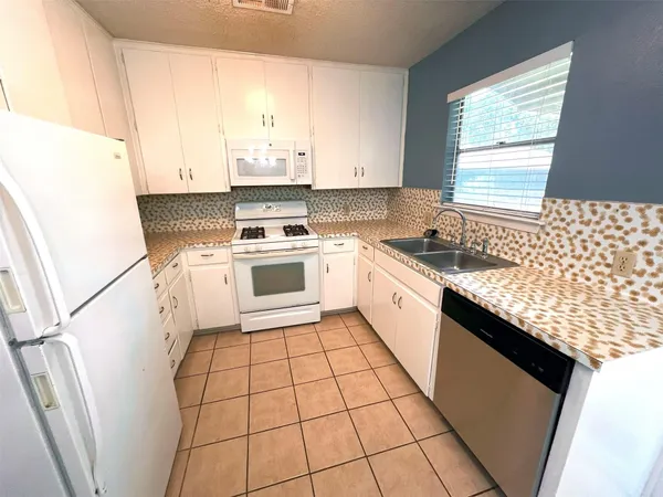 a kitchen with a sink a stove top oven and cabinetry