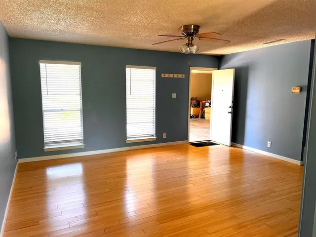 a view of an empty room with window and wooden floor