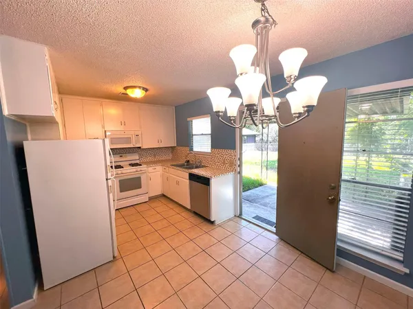 a kitchen with stainless steel appliances granite countertop a refrigerator a sink a stove and white cabinets