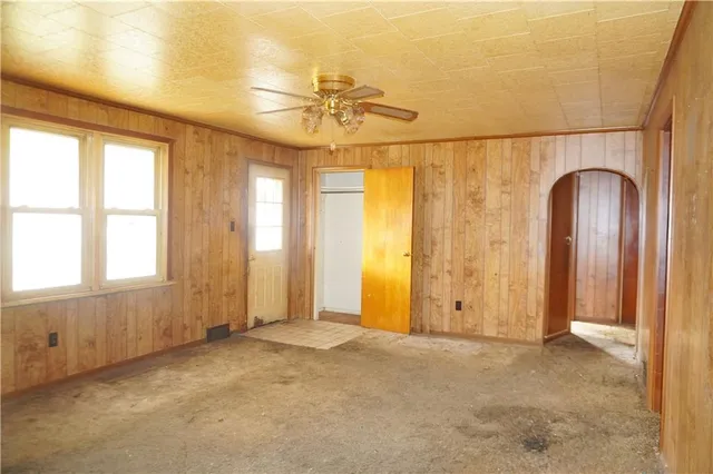 an empty room with windows and chandelier fan
