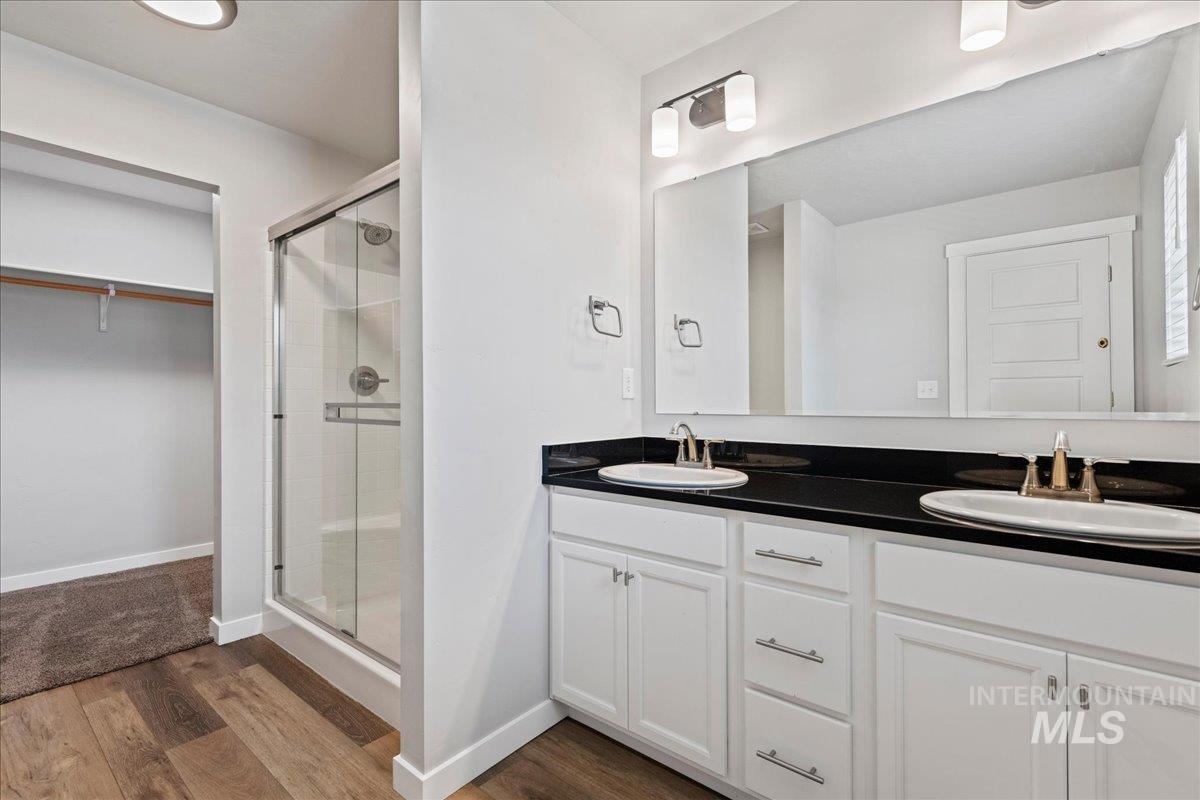 12535 West Victory Road Boise, ID 83709 - Photo 20 of 25 Dual vanity with white cabinetry, black countertop, and undermount sinks