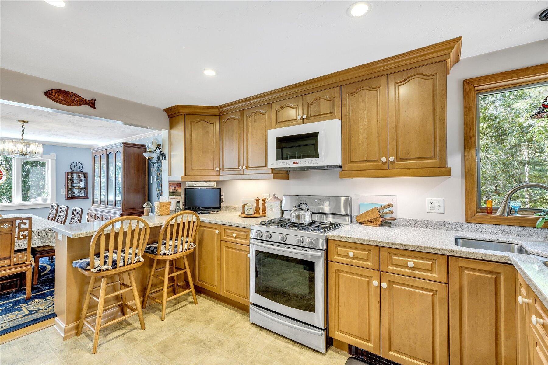 248 Wheeler Road Mashpee, MA 02649 - Photo 14 of 76 a kitchen with stainless steel appliances granite countertop a stove top oven a sink a dining table and chairs with wooden floor