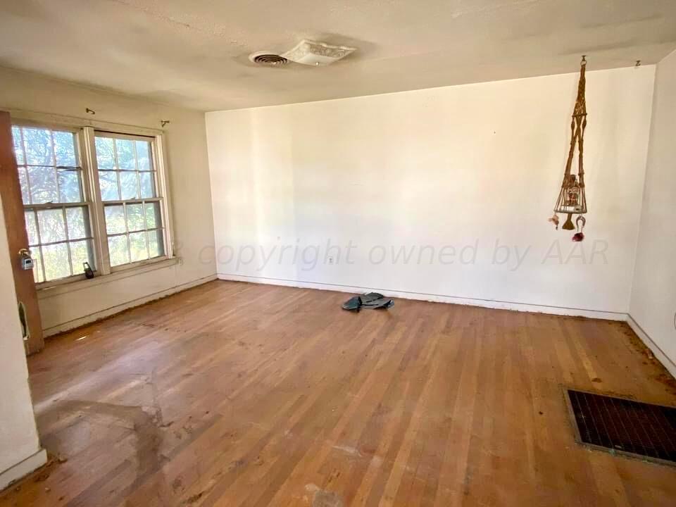 1303 Boyd Street Borger, TX 79007 - Photo 2 of 9 an empty room with wooden floor and windows