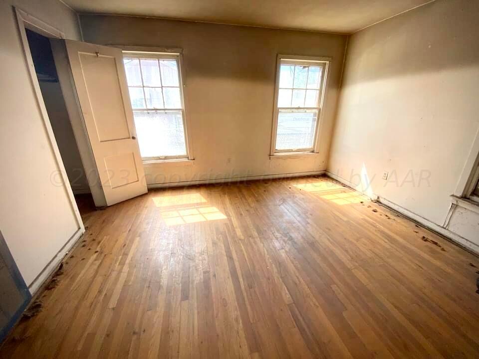 1303 Boyd Street Borger, TX 79007 - Photo 4 of 9 an empty room with wooden floor and windows
