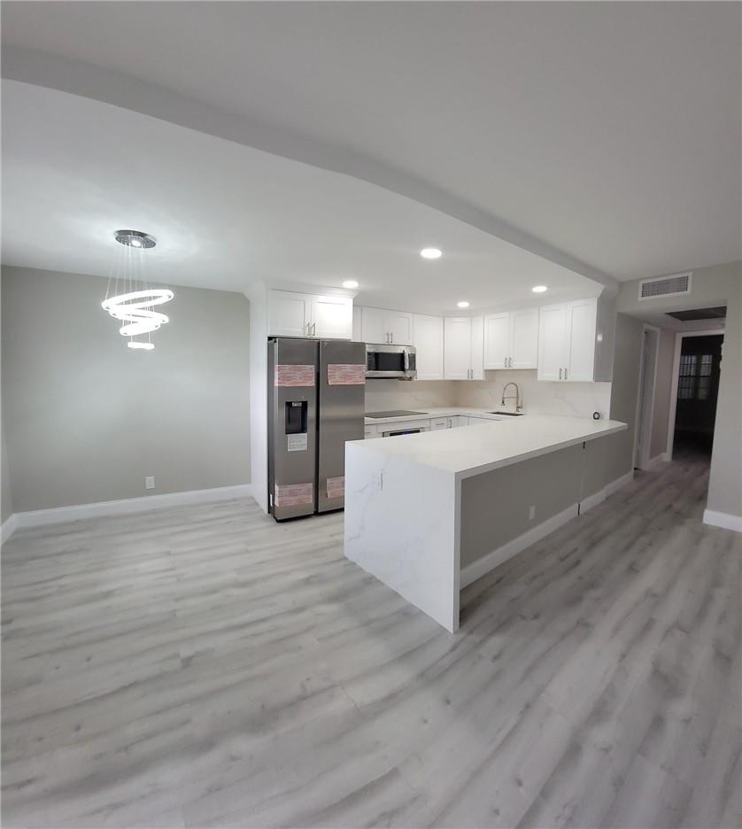 296 Brighton H, Unit H Boca Raton, FL 33434 - Photo 3 of 11 a large white kitchen with wooden floors and stainless steel appliances
