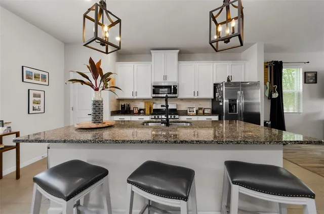 a kitchen with stainless steel appliances granite countertop a sink a stove and a refrigerator