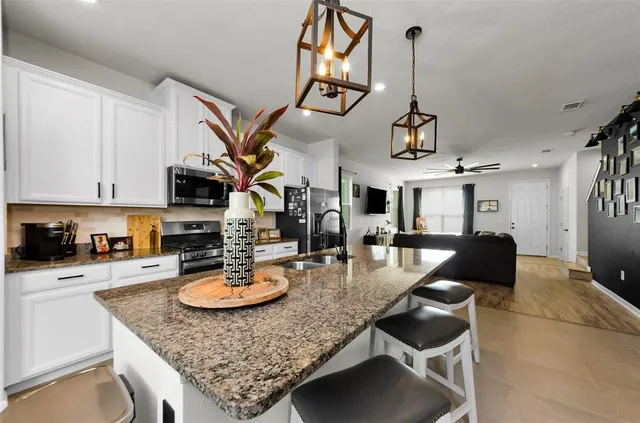 a kitchen with stainless steel appliances granite countertop grey cabinets a stove a sink and a white cabinets