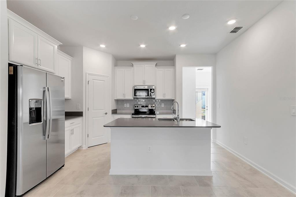1721 Good Neighbor Loop Kissimmee, FL 34744 - Photo 6 of 28 a kitchen with stainless steel appliances granite countertop a refrigerator and a stove