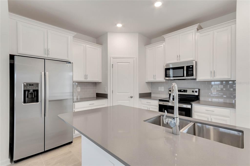 1721 Good Neighbor Loop Kissimmee, FL 34744 - Photo 7 of 28 a kitchen with stainless steel appliances a refrigerator a stove a sink and white cabinets
