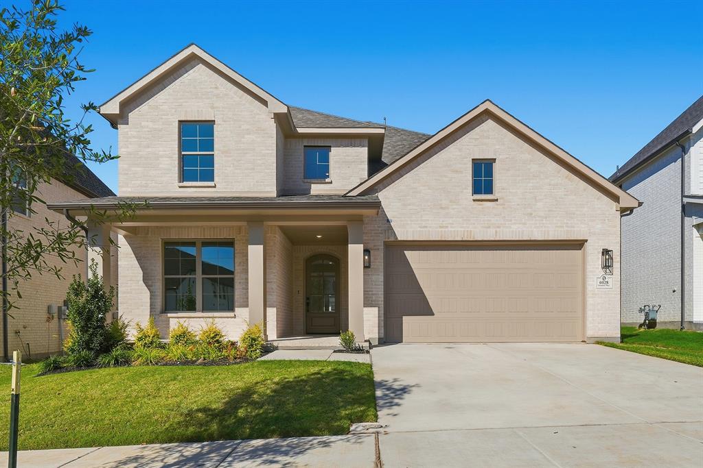 View of front of house featuring brick siding, covered porch, driveway, a front yard, and a garage