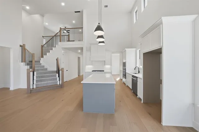 a living room with couches and kitchen view with wooden floor