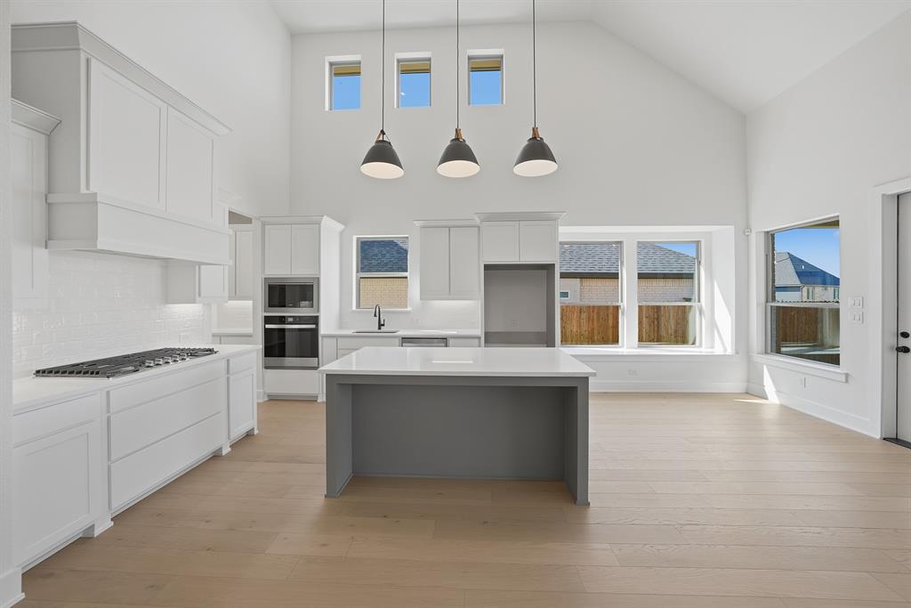 6028 Foxwheel Way Fort Worth, TX 76123 - Photo 9 of 37 Kitchen featuring a kitchen island, white cabinetry, backsplash, hanging light fixtures, and appliances with stainless steel finishes