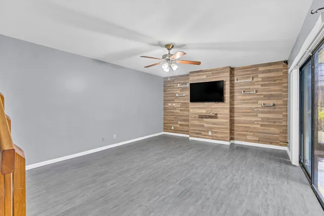 a view of an empty room with a ceiling fan and wooden floor
