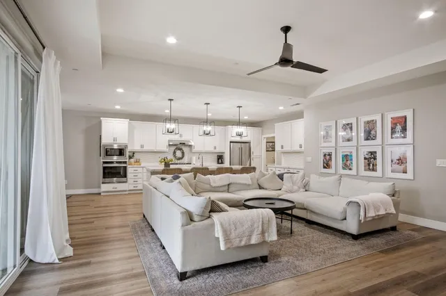 a living room with furniture kitchen view and a chandelier