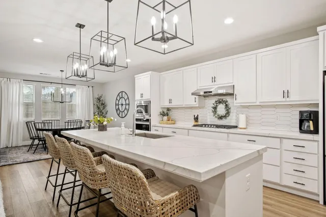 a kitchen with stainless steel appliances a table chairs and white cabinets
