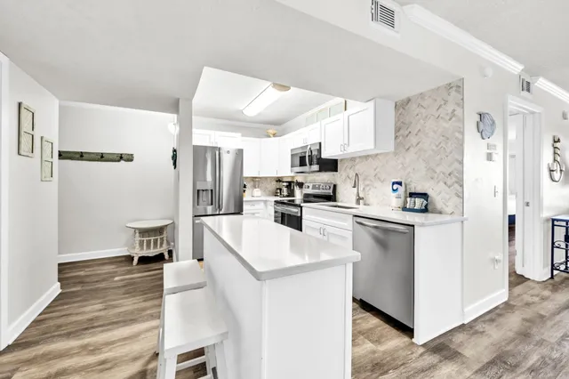 a kitchen with stainless steel appliances kitchen island granite countertop a refrigerator and a stove top oven