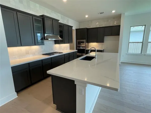 a kitchen with kitchen island granite countertop a sink a stove a refrigerator and cabinets